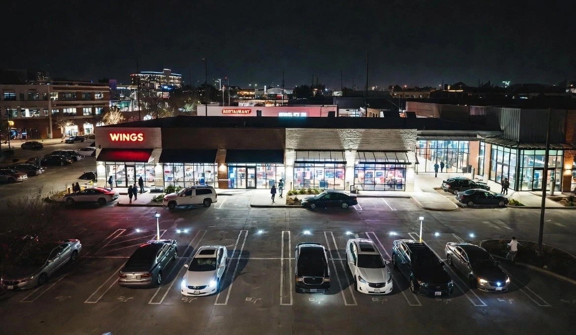 Busy retail shopping center parking lot at night in Greater Inwood Houston showing increased foot traffic thanks to bright commercial LED lighting