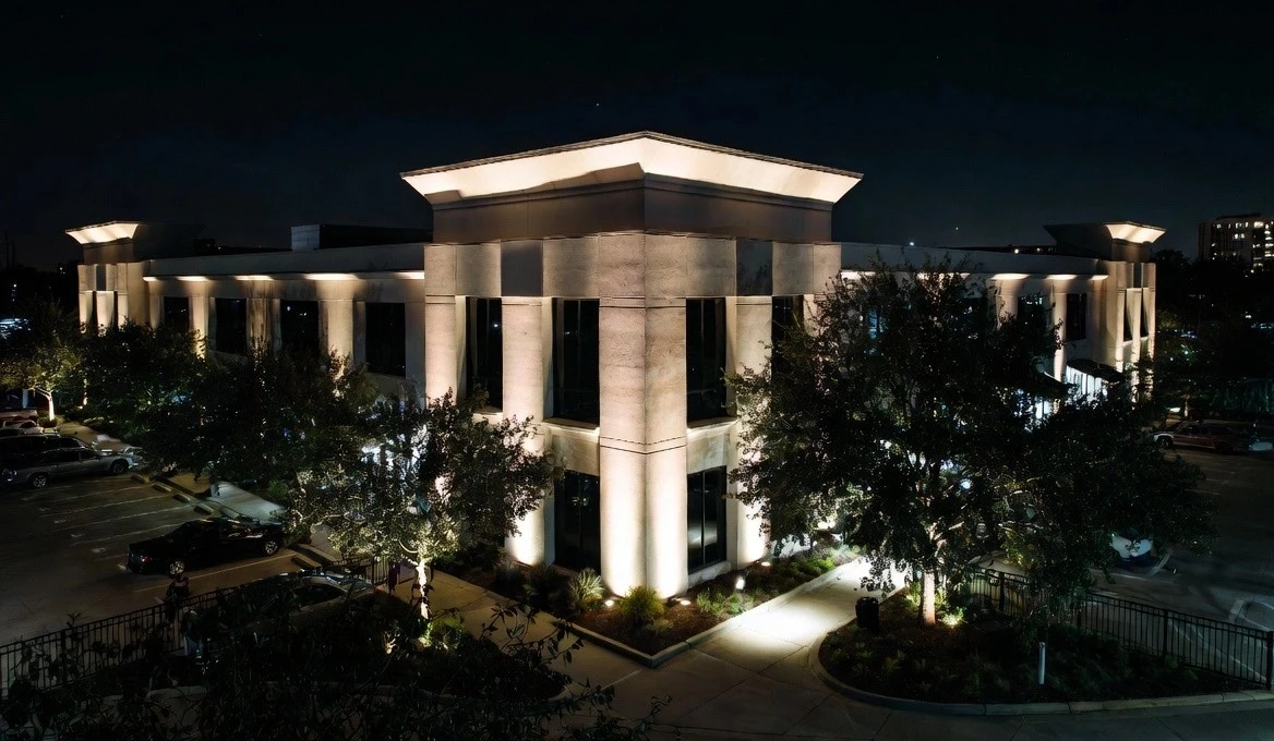 Elegant architectural facade lighting and landscape uplighting on commercial building at night in Houston improving property value and curb appeal