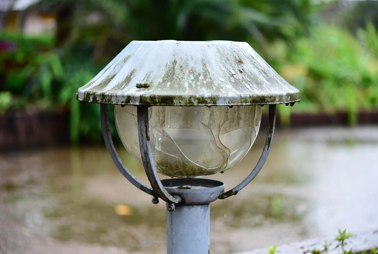 Corroded outdoor landscape light fixture showing water damage and rust common in Houston's humid climate